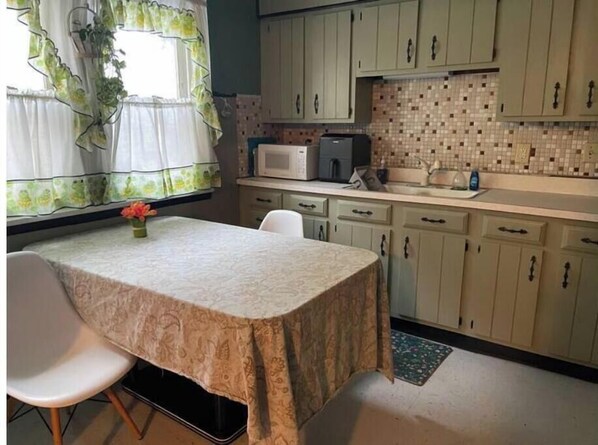 A small kitchen with a table and chairs, a microwave, and cabinets.