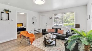A modern living room with a sofa, coffee table, and a large window with blinds.