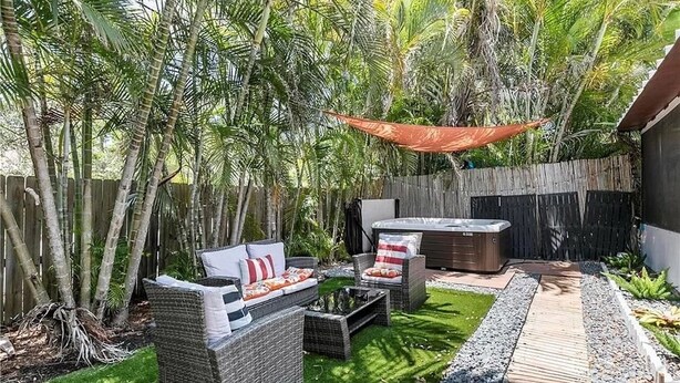 An outdoor patio with wicker furniture, a hot tub, and a wooden deck.