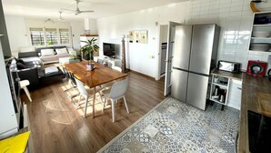A modern apartment with a dining area, kitchen, living room, and a balcony.