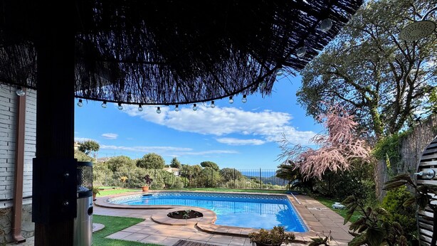 A backyard with a swimming pool, a wooden deck, and a pergola.