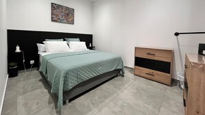 A modern bedroom with a bed, bedside table, dresser, ceiling fan, and an air conditioning unit. - Le Ti Songe (Saint-Joseph)