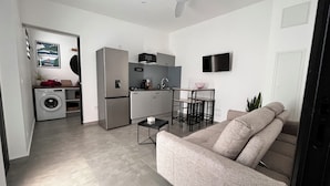 A compact living space with a kitchenette, a sofa, a dining table, and a ceiling fan. - Le Ti Songe (Saint-Joseph)