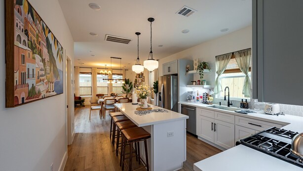 A modern kitchen with a central island, bar stools, pendant lighting, and a large window with curtains. - Cozy home near Med Center, NRG, UH, Downtown, Museum (Houston)