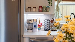 A modern kitchen with a stainless steel refrigerator, a white countertop, a coffee maker, and a hanging plant. - Cozy home near Med Center, NRG, UH, Downtown, Museum (Houston)