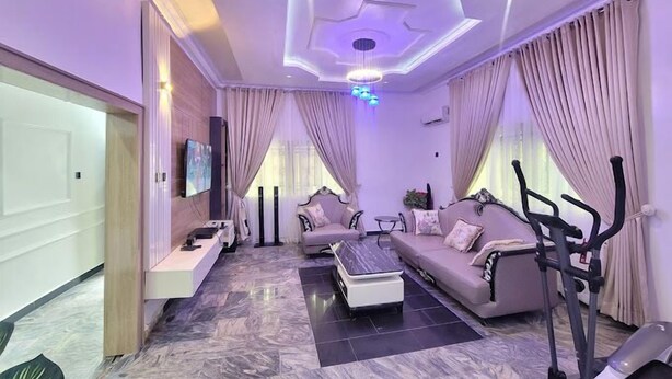 A modern living room with a sofa, a coffee table, an exercise bike, and a TV on the wall.