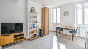 Una sala de estar moderna con televisor, mueble de madera para entretenimiento y un comedor con mesa y sillas.
