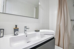 Ein Badezimmer mit einem weißen Waschbecken, einem Spiegel, einem Handtuch und einer Duschvorhang.