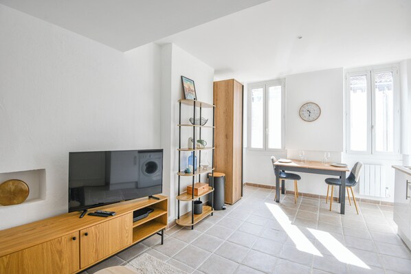 Ein modernes Wohnzimmer mit Flachbildfernseher, einer Holzunterhaltungsecke und einem Essbereich mit Tisch und Stühlen.