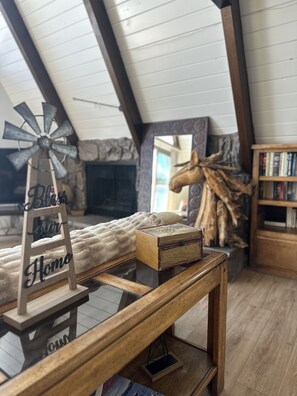 A cozy loft bedroom with a sloped ceiling, a windmill decoration, a horse sculpture, a bookshelf, and a plush bed.