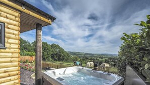 Eine Holzblockhütte mit Whirlpool und Blick auf die Landschaft.