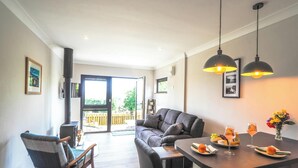 Eine moderne Küche mit Essbereich, einer Couch und Blick durch eine offene Tür auf einen Balkon.