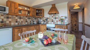 A kitchen with wooden cabinets, a tiled backsplash, and a dining area with a table set for two.