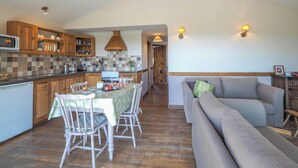 A kitchen with wooden cabinets, a dining table with chairs, a sofa, and a ceiling fan.