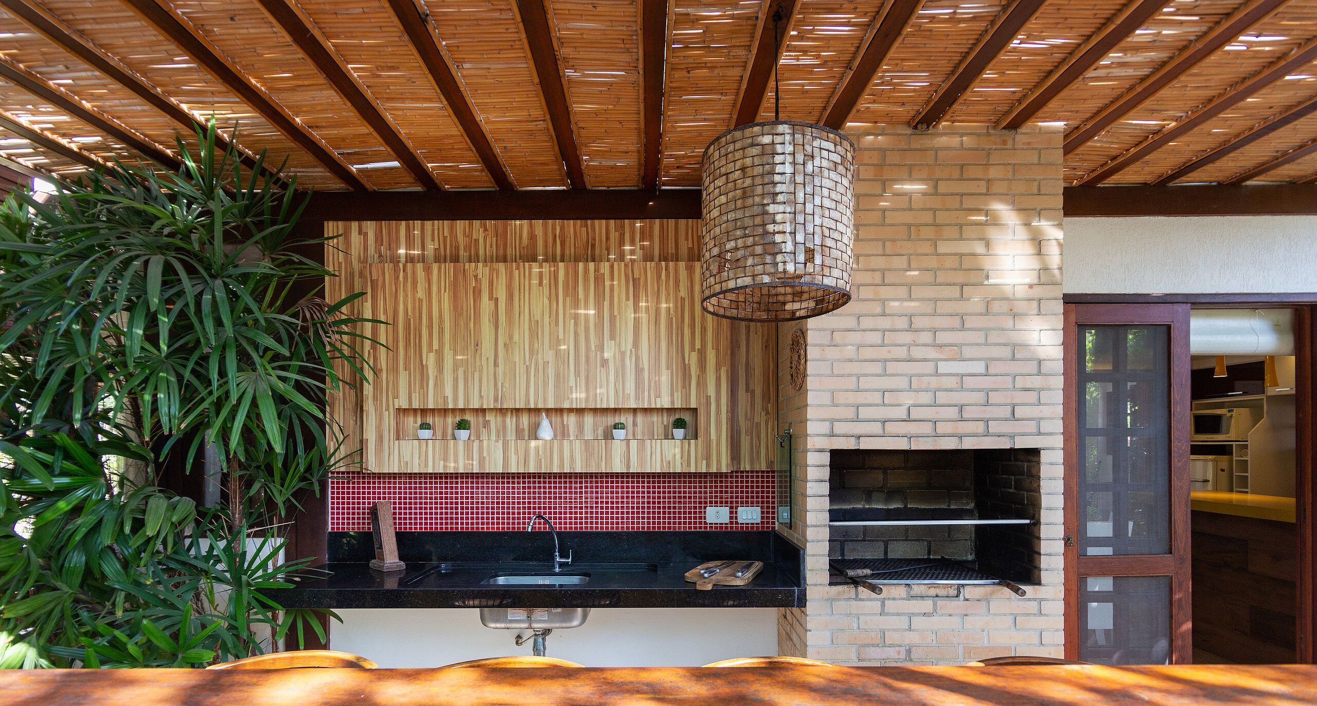 Una cocina con horno de ladrillo, vigas de madera en el techo y una lámpara colgante.