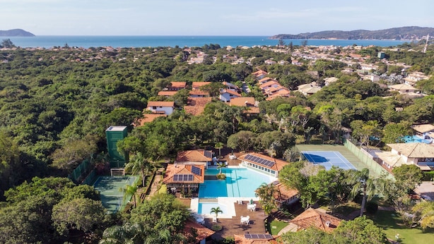 Vista aérea de un complejo turístico con piscina, rodeado de exuberante vegetación y un paisaje costero.