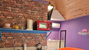 Eine Küche mit Backsteinwand, einer roten Mikrowelle, blauen Schränken und einem kleinen Kühlschrank.