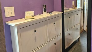Ein Badezimmer mit violetten Wänden, einem weißen Waschtisch mit Schubladen, einem Spiegel und einer Klimaanlage über dem Waschtisch.