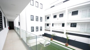 A modern building with multiple floors, a glass balcony, and potted plants.