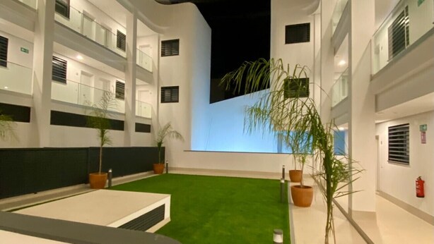A modern building with multiple floors, outdoor seating areas, and potted plants.
