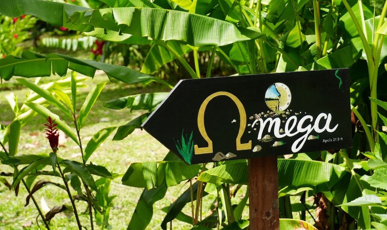 Un letrero con el logotipo de Omega y la palabra 'mega' en un jardín.