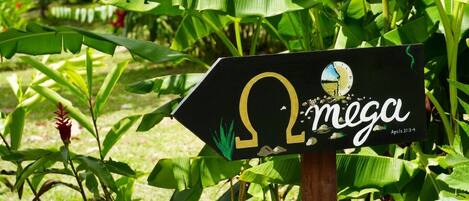 Un letrero con el logotipo de Omega y la palabra 'mega' en un jardín.
