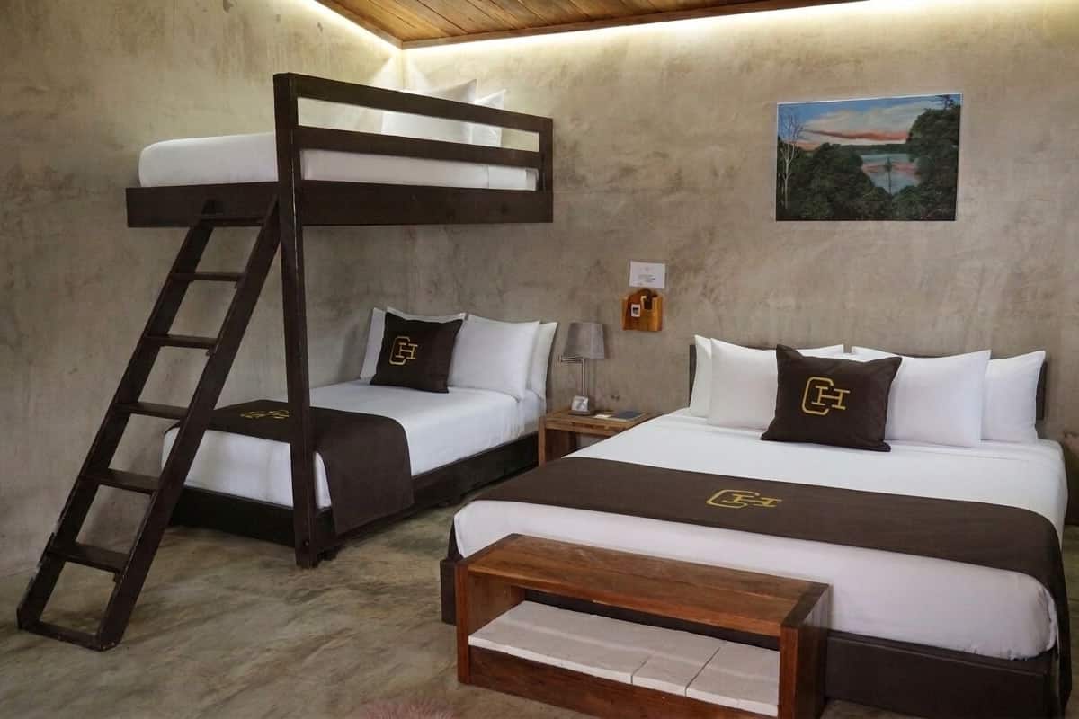 Habitación con literas, una escalera, dos mesitas de noche, una lámpara y un cuadro en la pared.