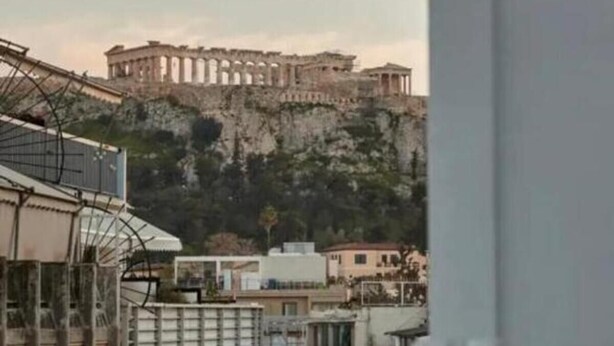 A view of ancient ruins atop a hill, with modern buildings in the foreground. - Athens City Suites (Athens)