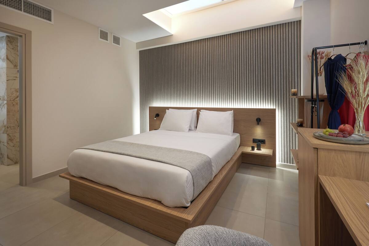 Quarto moderno com cama de madeira, mesa de cabeceira e escrivaninha com uma fruteira.