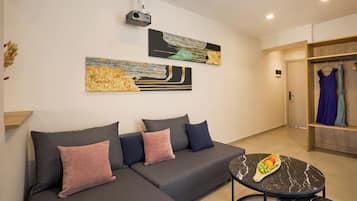 A modern living room with a grey sectional sofa, a round black marble coffee table with fruit, and abstract wall art.