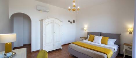 A hotel room with a bed, a desk with a lamp, a chair, a wardrobe, and a breakfast tray.