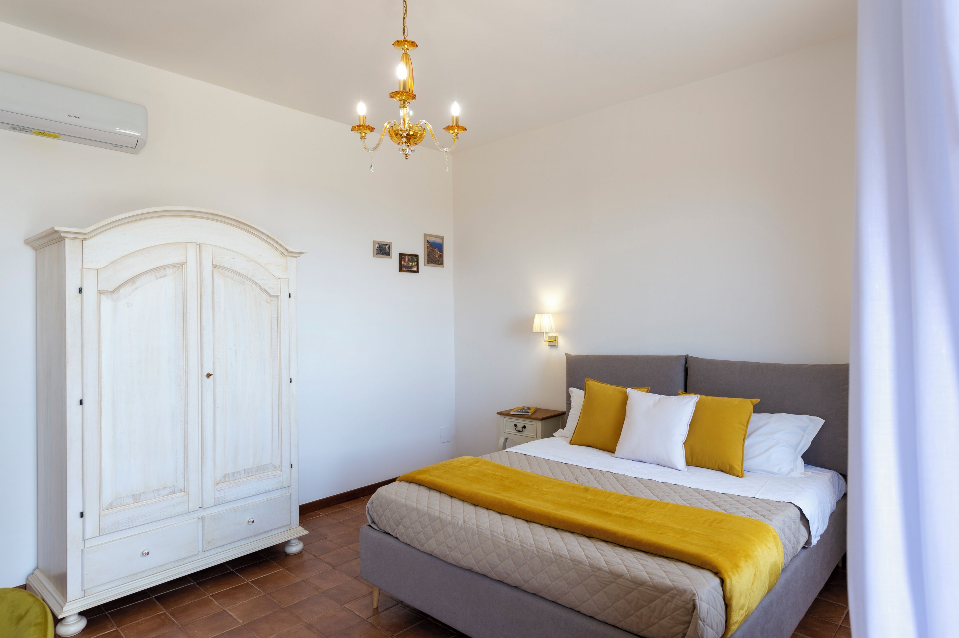 Une chambre à coucher avec un lit, une armoire, un lustre et une table de chevet.