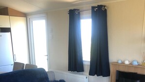 Ein gemütlicher, kompakter Wohnbereich mit einer Couch, einem kleinen Holztisch, einem Kamin und einem Fenster mit Vorhängen.