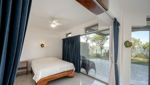 Une chambre à coucher avec un lit, un ventilateur de plafond, une fenêtre et une vue sur l’extérieur.