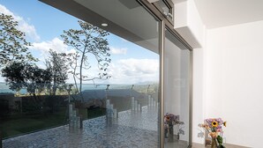 Un intérieur moderne avec une grande porte vitrée donnant sur un patio doté d’un sol en mosaïque et offrant une vue sur l’extérieur.