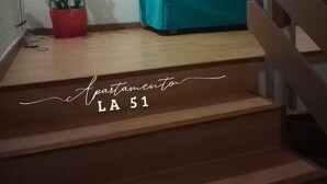 Un escalier mène à un espace de vie où se trouve un canapé turquoise et un tableau encadré accroché au mur.