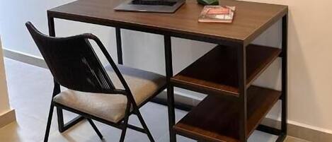 Un pequeño espacio de trabajo con una laptop, una silla y un cuadro en la pared.