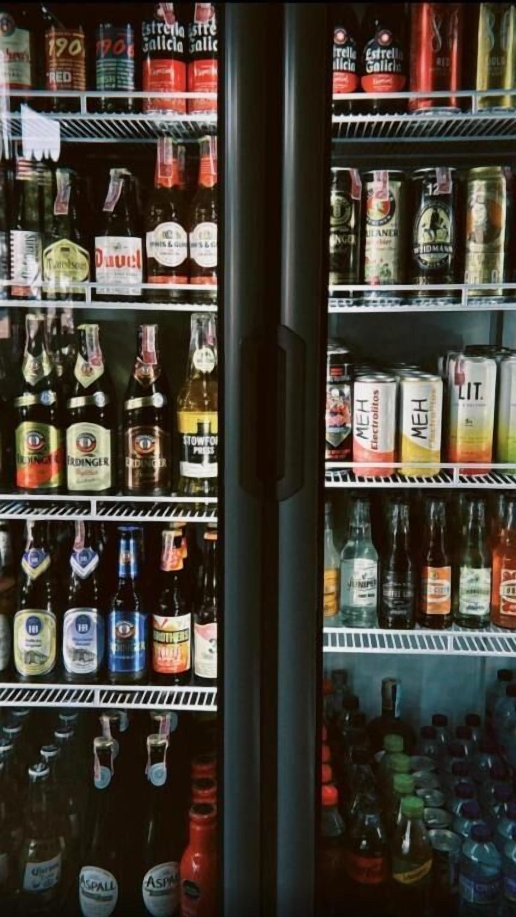 Un expositor refrigerado con diversas bebidas embotelladas, incluyendo vino y cerveza.