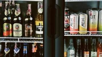 Un expositor refrigerado con diversas bebidas embotelladas, incluyendo vino y cerveza.