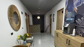 A hallway with a reception desk, a water dispenser, and a patterned wall. - Hotel Star 37 Av (Ibague)
