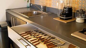 A kitchen with a built-in utensil drawer, a blender, and a tiled backsplash.