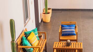 A sunlit patio with wooden furniture, potted cacti, and decorative wall art.
