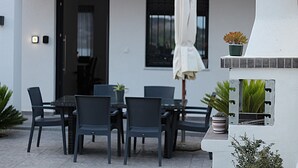 Eine Terrasse im Freien mit Tisch und Stühlen, einem Schirm und Kübelpflanzen.