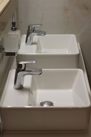 Ein Badezimmer mit drei Waschbecken und einer Seifenspender.