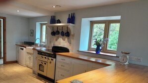 A kitchen with a wooden countertop, white cabinets, an oven, a sink, and a window with a view of greenery. - Canal-side 5-bed Cottage - Sleeps 10, Pet Friendly (Stoke-on-Trent)