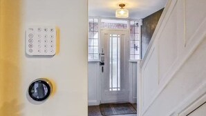 Un pasillo con una puerta, un teclado numérico y un mirilla.