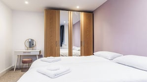 Un dormitorio moderno con una cama grande, un armario de madera, un escritorio y un espejo.