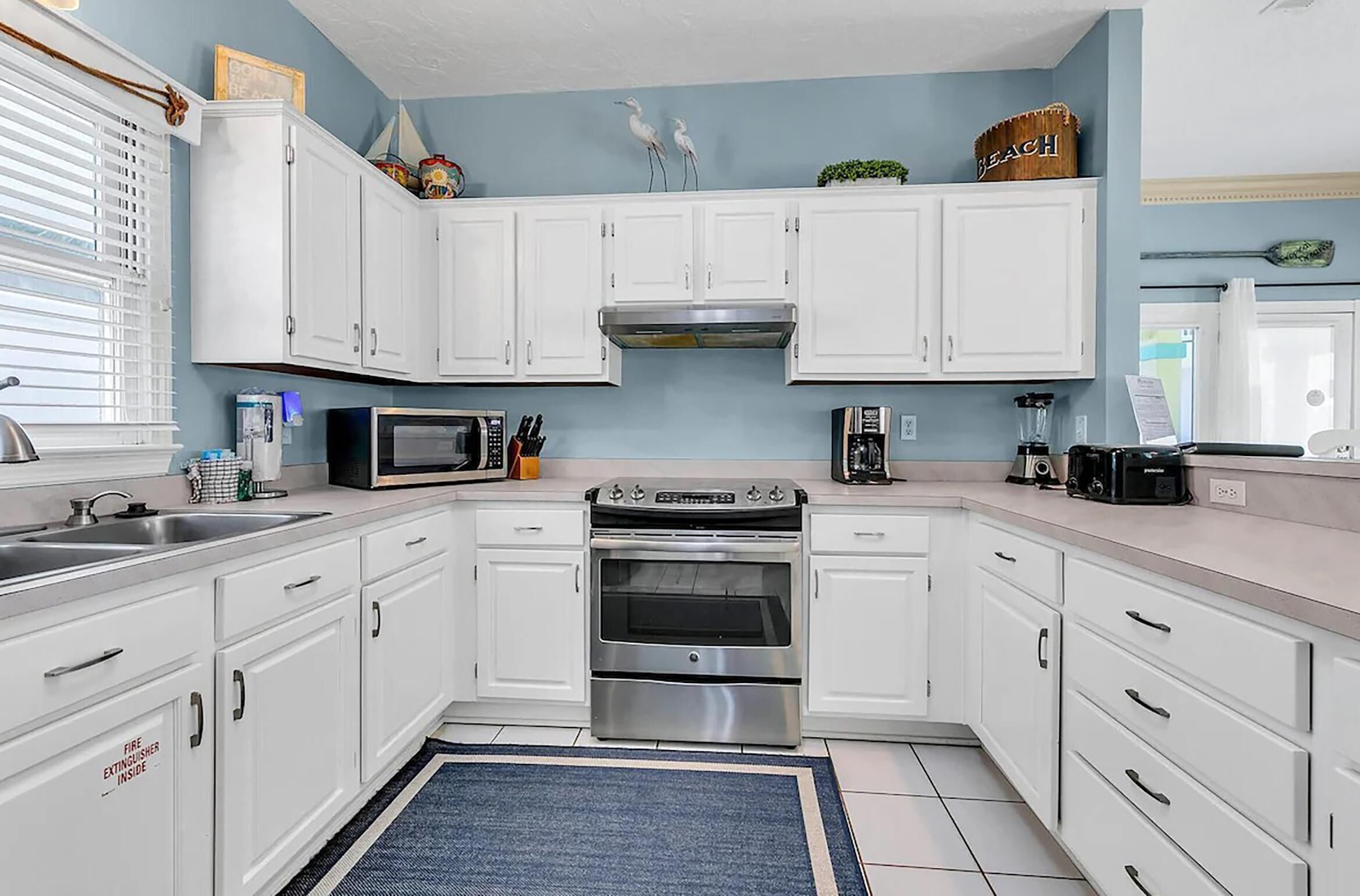 A kitchen with white cabinets, a stainless steel oven, a microwave, and a coffee maker.
