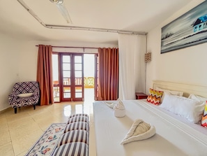 A hotel room with a bed, a chair, a small table, and a painting on the wall. - Shanzu Oceanfront Apartments (Mombasa)