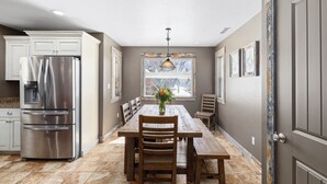 A kitchen with a stainless steel refrigerator, wooden dining table, and chairs. - Large house with lots of space. Just minutes away from national forest. (Thayne)